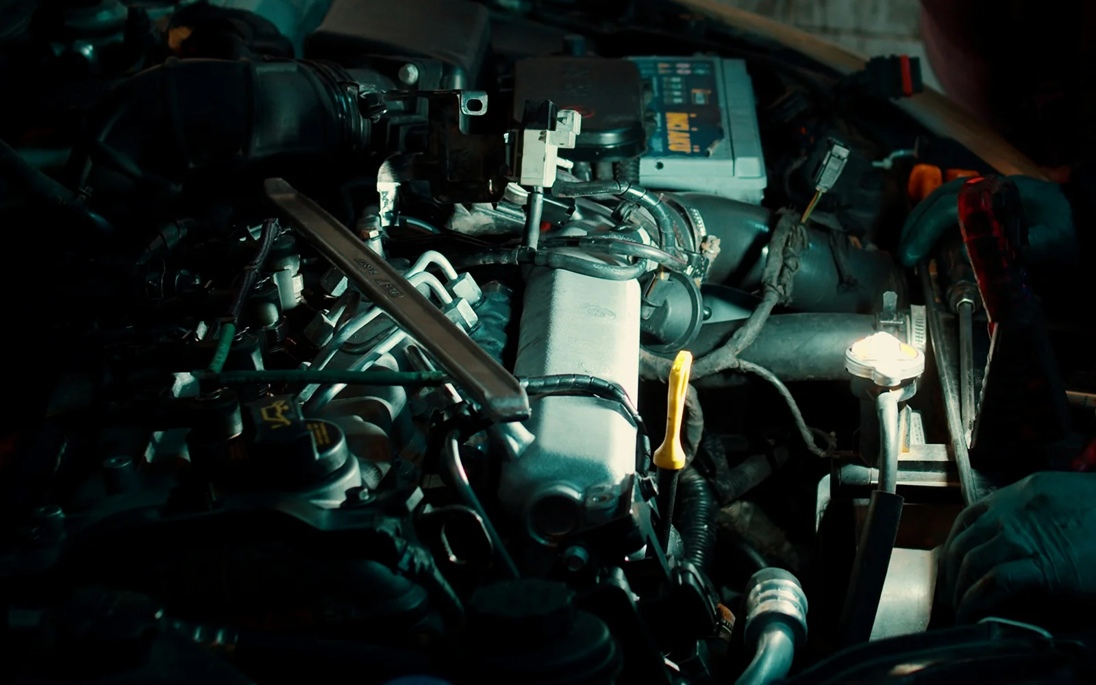 Mechanic working on a car engine with the bonnet open in a workshop